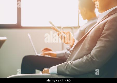 business man with modern people technology concept. two male businessman using laptop computer and smartphone in waiting area. Stock Photo