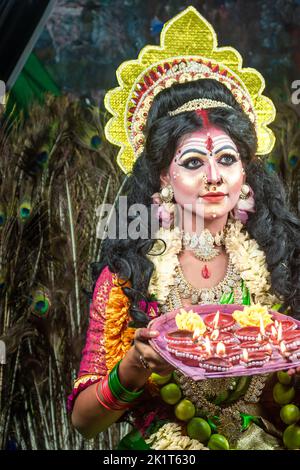 Concept Agomoni shoot with black haired Indian brunette woman face with perfect makeup and wearing jewelers with traditional dress like goddess Stock Photo