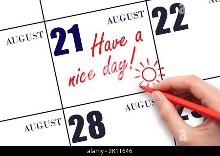 21st day of August. The hand writing the text Have a nice day and drawing the sun on the calendar date August 21. Save the date. Summer month, day of Stock Photo