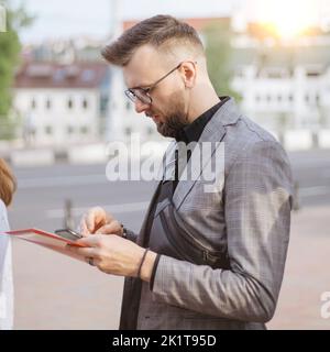young man with a smartphone standing among a group of tourists. Stock Photo