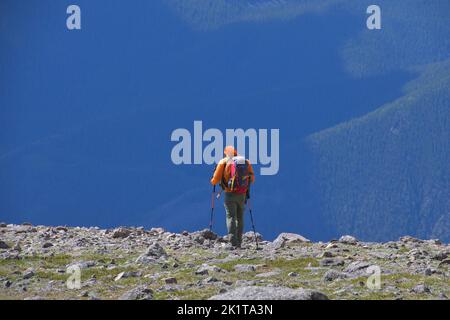 A man in full mountain walking gear and walking poles makes his way back down from Mount Elbert in Colorado USA Stock Photo