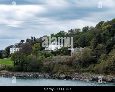 A hill on the shore of the bay. Several buildings and trees on the hill. Glandore is a village in the south of Ireland. Beautiful clouds, dramatic lan Stock Photo