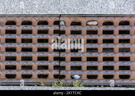 Rusty cast-iron grate closes a drainage channel on one of Dresden's city streets. Stock Photo