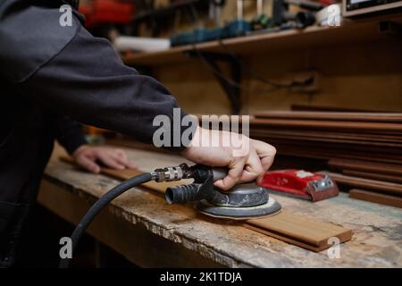 Close up of unrecognizable male worker sanding wooden boards in workshop and using electric tools, copy space Stock Photo