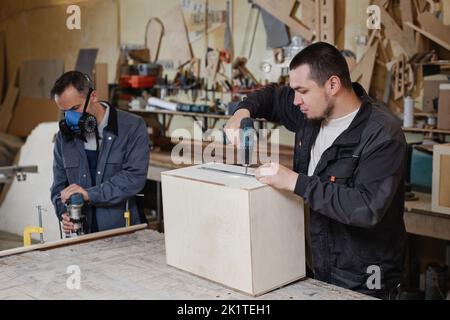 Portrait of two male workers building wooden furniture in factory workshop, copy space Stock Photo