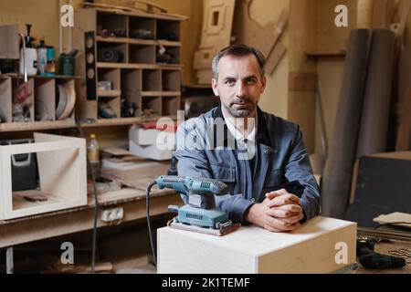Portrait of senior male worker looking at camera while standing in factory workshop, copy space Stock Photo