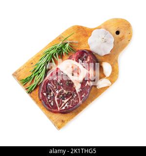 Fresh raw meat beef steak with bone with spices, rosemary, garlic and olive oil on wooden cutting board isolated on white background. Top view. Flat l Stock Photo