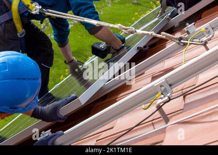 Workers installing solar panels on roof. Alternative energy concept. Stock Photo