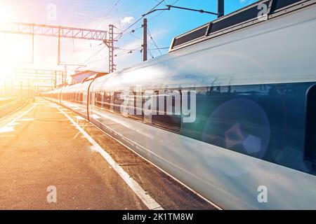 Passenger railway carriage train on railroad station at sunset. Stock Photo