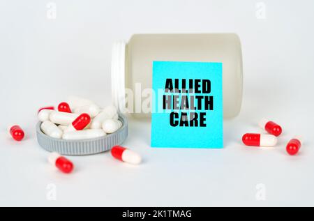 Medical concept. On a gray background, a jar, capsules and a sign with the inscription - Allied Health Care Stock Photo