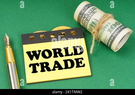 Business concept. On a green surface are a pen, dollars and yellow stickers with the inscription - World Trade Stock Photo