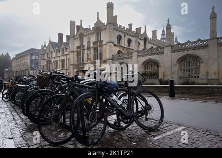 Bicycles parked on a wet street in front of the buildings of King's College. It's raining, white rain dashes and stripes on the bikes and background Stock Photo