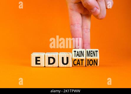 Education and edutainment symbol. Concept words Education and edutainment on wooden cubes. Teacher hand. Beautiful orange table orange background. Edu Stock Photo