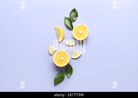 Composition with pieces of ripe lemon and leaves on lilac background Stock Photo