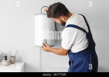 Male plumber adjusting boiler in bathroom Stock Photo