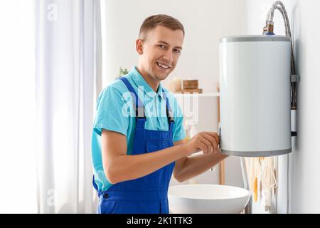 Male plumber adjusting boiler in bathroom Stock Photo