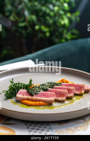 Juicy Tuna tagliata cut into slices on carrot puree. Beautiful serving, traditional Italian cuisine, copy space. food concept Stock Photo