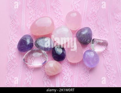 Semi-precious stones of different colors in processed form. Amethyst crystals, rose quartz and rock crystal on pink lace. Stock Photo