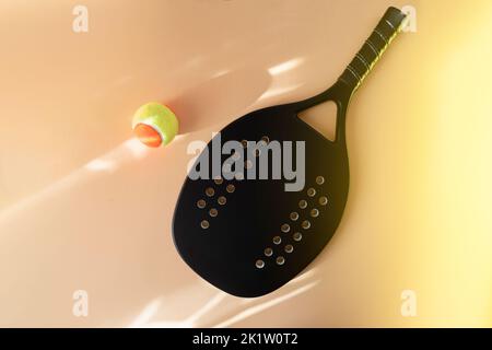 Black professional beach tennis racket and ball on beige background. Horizontal sport theme poster, greeting cards, headers, website and app Stock Photo