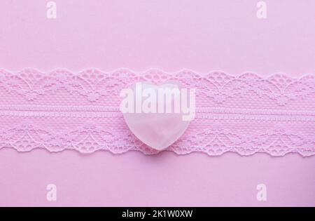 Heart shaped rose quartz crystals on pink lace. Semi-precious minerals are a love talisman for women. Stock Photo