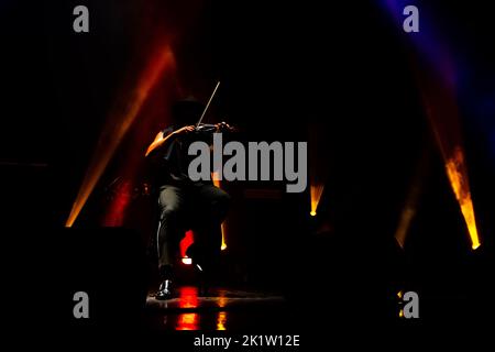 Closeup of man playing violin on stage, hands with violin on dark background Stock Photo