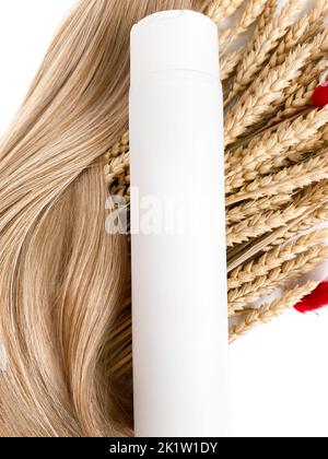 A strand of blond hair with a bottle of shampoo on a white background. Close-up. Stock Photo