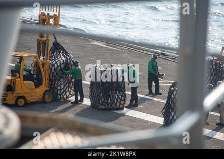 220920-N-BR419-1123 PHILIPPINE SEA (Sept. 20, 2022) Sailors transport cargo on the flight deck of the U.S. Navy’s only forward-deployed aircraft carrier, USS Ronald Reagan (CVN 76), during a replenishment-at-sea in the Philippine Sea, Sept. 20. Replenishments-at-sea increase the capabilities of the U.S. Navy’s carrier force, allowing ships to stay at sea indefinitely by providing, fuel, food and supplies anywhere in the world. Ronald Reagan, the flagship of Carrier Strike Group 5, provides a combat-ready force that protects and defends the United States, and supports alliances, partnerships an Stock Photo