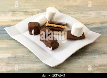 Bite Size smore candies with chocolate pieces on graham crackers and marshmallows on snack plate Stock Photo