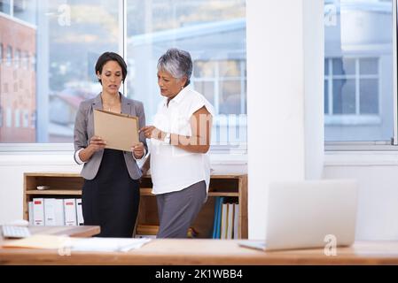 Whats the status on that project. two businesswomen discussing paperwork in the office. Stock Photo