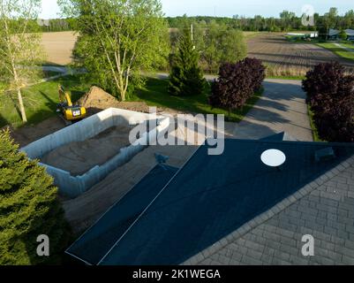 An aerial view above a home under construction with a SpaceX Starlink satellite internet dish installed on the roof, seen late in the day. Stock Photo