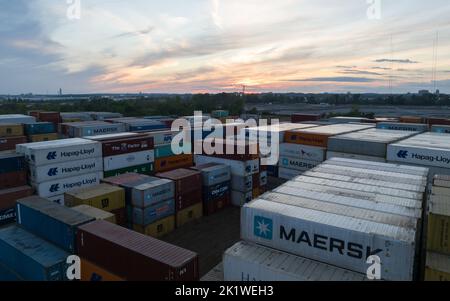 An aerial view above a shipping terminal in a vast industrial sector seen at dusk; large, global shipping couriers have containers stacked in storage. Stock Photo
