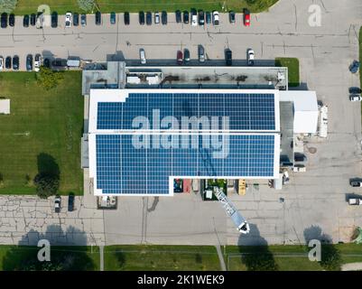 A top-down, overhead view looking down on the building with solar panels installed across the roof, seen on a sunny day. Stock Photo