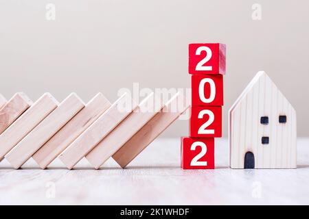Red 2022 cube blocks stop falling blocks protect house miniature. fall Business, Home Insurance, investment, Crisis, Economic recession, New Year, Rea Stock Photo
