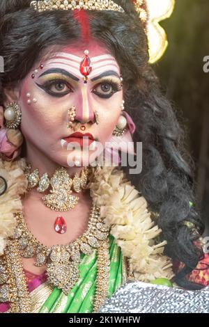Concept Agomoni shoot with black haired Indian brunette woman face with perfect makeup and wearing jewelers with traditional dress like goddess Stock Photo