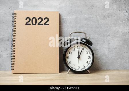 2022 Happy New Year with blank notebook, black retro alarm clock and wooden number. countdown, Resolution, Goals, Plan, Action and Mission Concept Stock Photo