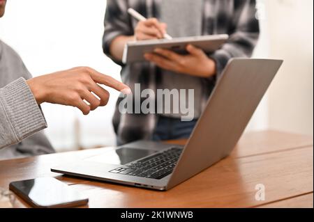 A professional male programmer working with his assistant in the office, looking at laptop screen. cropped image Stock Photo