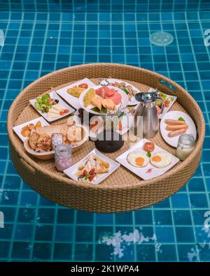 Top view of floating breakfast in the swimming pool, floating breakfast in the pool with bread eggs and fruit, and coffee Stock Photo
