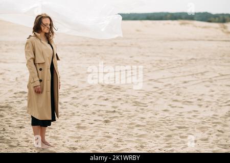 Desperate woman. Mistake regret. Betrayal sorrow. Nature landscape. Portrait of depressed lady in beige trench coat with flying away hair standing bar Stock Photo