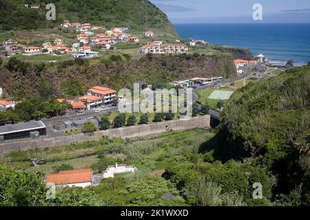 Valley with road stretching between green hillside from Sao Vicente down to the Atlantic ocean on the North coast of Madeira Stock Photo