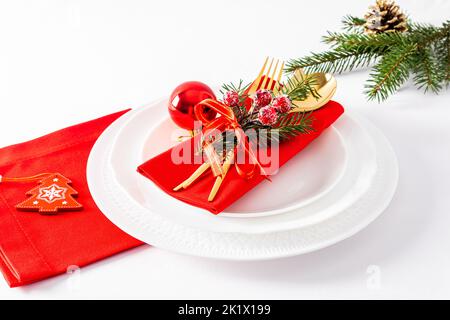 white plates with red napkins and Christmas decorations on a white background. festive serving in the classical style Stock Photo