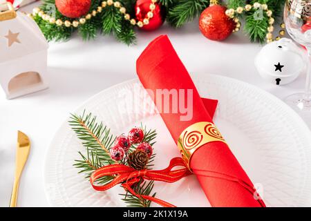 beautiful New Year's table setting. elegant napkins with decorations on a white reflected plate. twigs of spruce Stock Photo