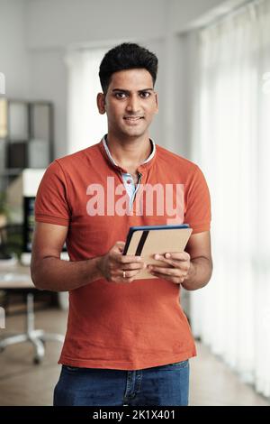Positive software engineer holding tablet computer and smiling at camera Stock Photo