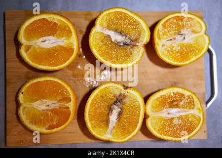Rotten inside orange. Mold on fruit pulp. Spoiled orange on chopping board. Rottening fruit gradient. Cut in halves rotten orange fruit with fungus Stock Photo