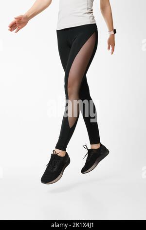 slim female legs in black sport leggings jumping Stock Photo