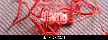 Tangled red wired headphones on gray background Stock Photo