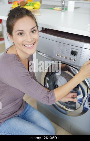 close-up of woman hand loading dirty clothes in washing machine Stock Photo