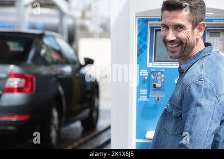 person paying coins to self service automatic car cleaning machine Stock Photo