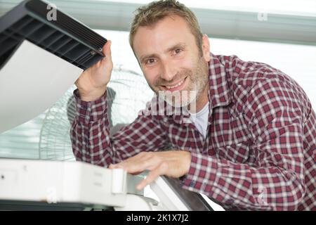 hardware repairman repairing broken printer fax machine Stock Photo