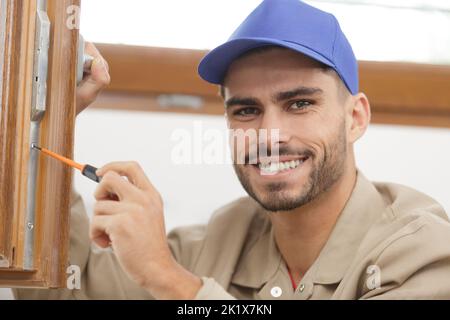 young man contractor screwing window handle mechanism Stock Photo