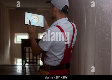 smart home and technology concept - close up of male hands pointing finger to tablet pc computer with house settings on screen Stock Photo